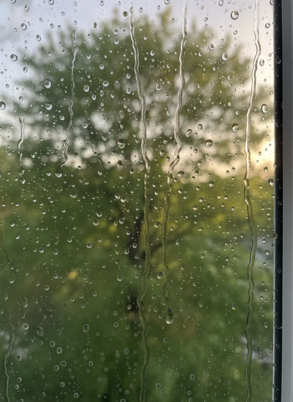 Raindrops sliding down a window with blu... 1